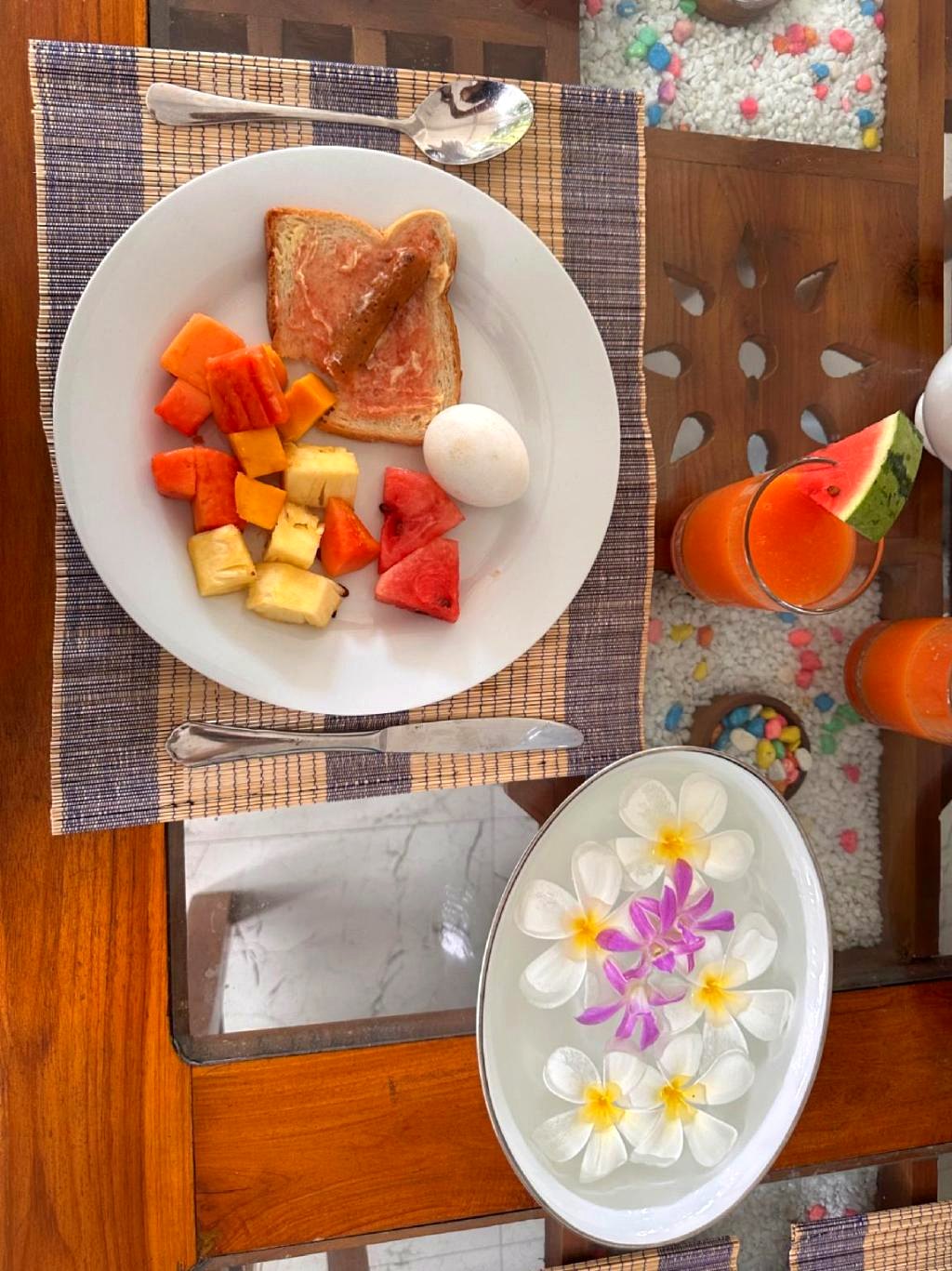 Villa Estuary breakfast — fresh fruit, egg, toast, juice and frangipani flowers